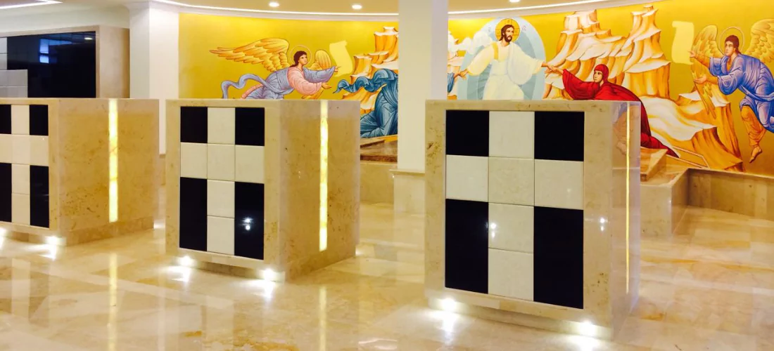 Criptas Mural religioso con detalles en mármol beige y negro, acompañado de un fondo vibrante con figuras angelicales y Jesús