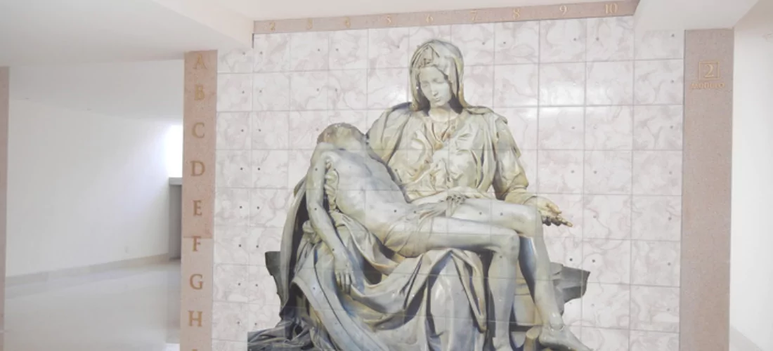 Criptas Muro de nichos en mármol beige con imagen de la Piedad y detalles en dorado