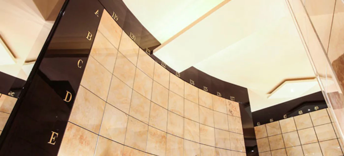 Criptas Muro de nichos curvo en tonos beige, marcado con coordenadas alfabéticas y numéricas para la organización de los nichos, ofreciendo un diseño sobrio y elegante