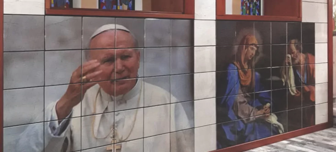 Criptas Mural en mosaico que muestra una imagen de Juan Pablo II junto a una escena religiosa de la Virgen y San José, con vitrales en la parte superior