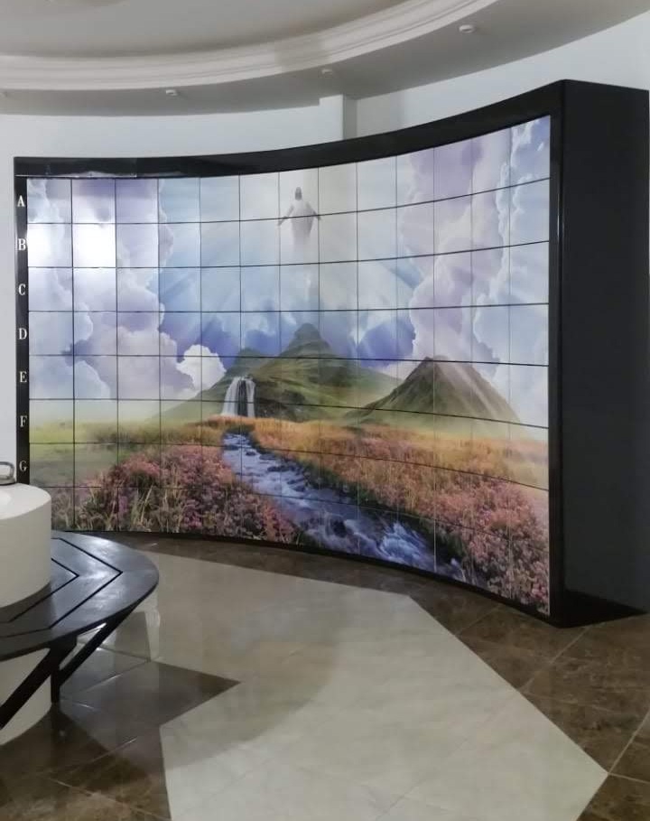 Criptas Mural curvo de mosaico que muestra un paisaje con montañas, cascada y figura celestial en el cielo