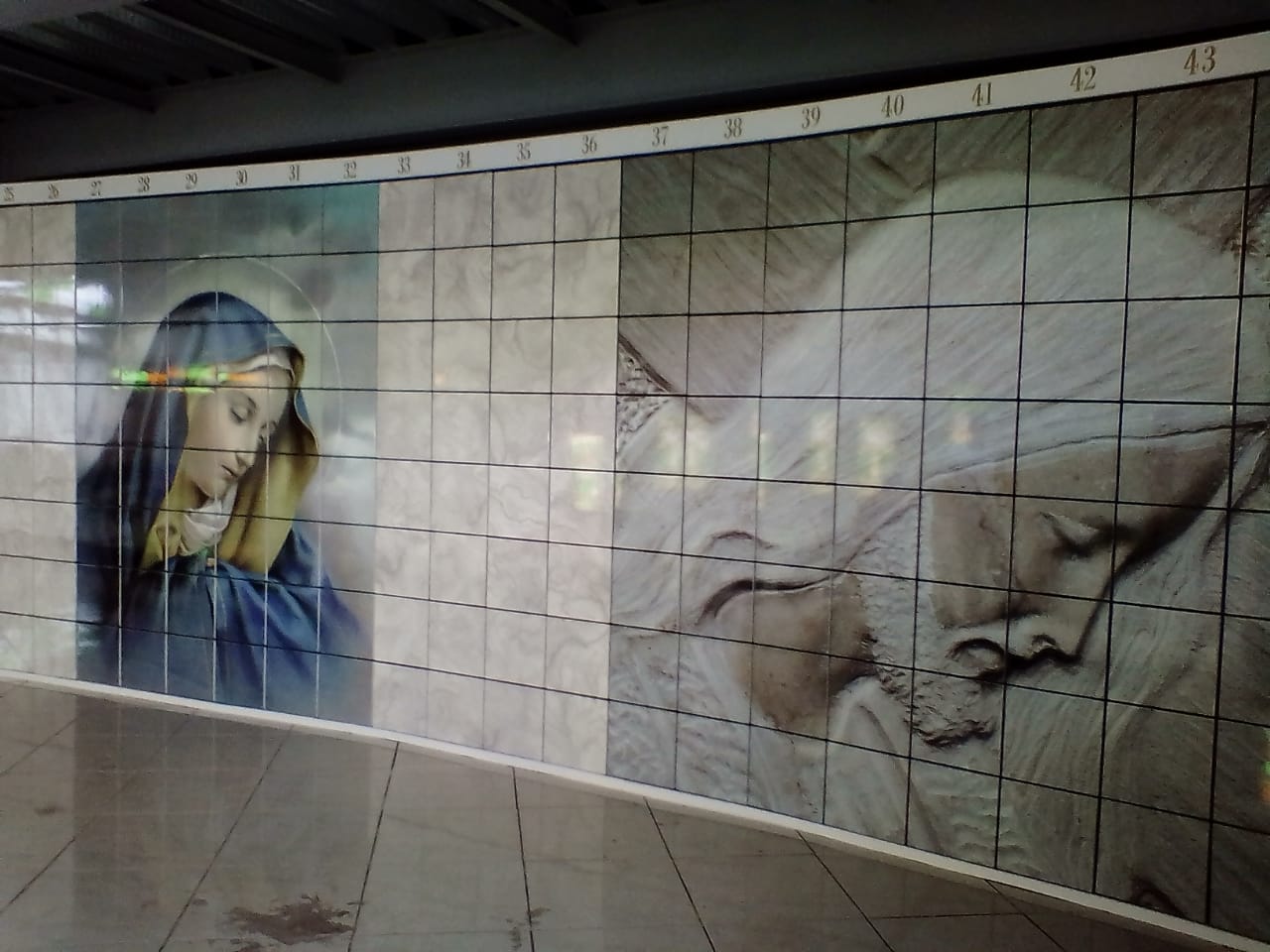 Criptas Mural en mosaico que representa imágenes religiosas de la Virgen María y Cristo, con numeración en la parte superior